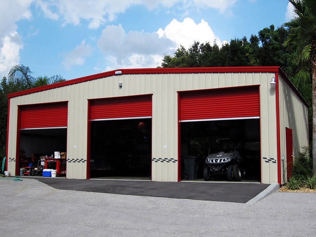 tan steel building garage with red trim, three garage doors