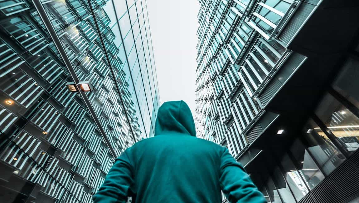 Man wearing hood facing upward high-rise smart buildings