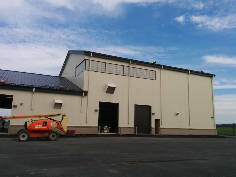 Workers on the roof of Puente Construction Enterprises industrial hangar with framed openings, walk doors.